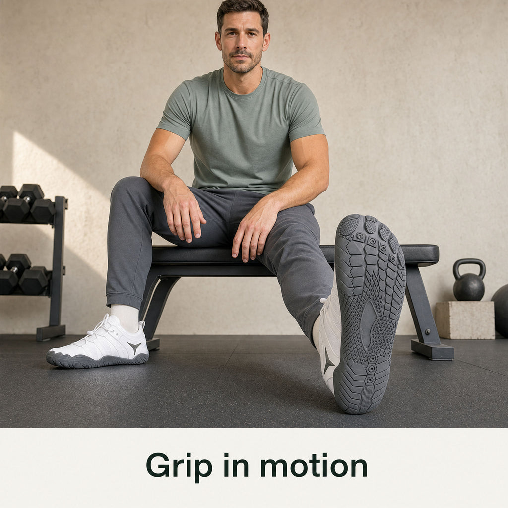 White Barevon shoes during seated left-ankle mobility, showing the correctly oriented left outsole with heel grounded.