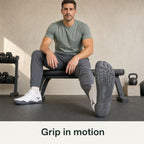 White Barevon shoes during seated left-ankle mobility, showing the correctly oriented left outsole with heel grounded.