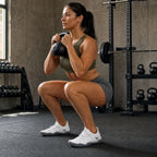 Woman performing a kettlebell goblet squat in White Barevon Original shoes.
