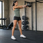 Woman performing a kettlebell swing in White Barevon Original shoes.