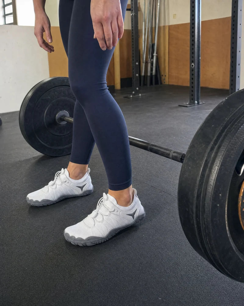 White Barevon shoes beside a barbell.